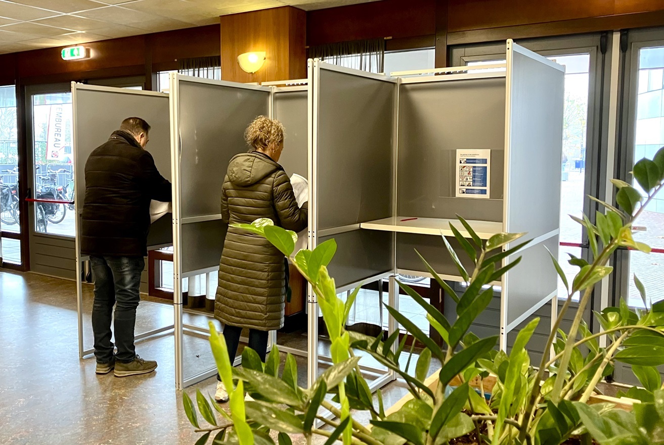 Twee mensen staan apart in een stemhokje op het gemeentehuis